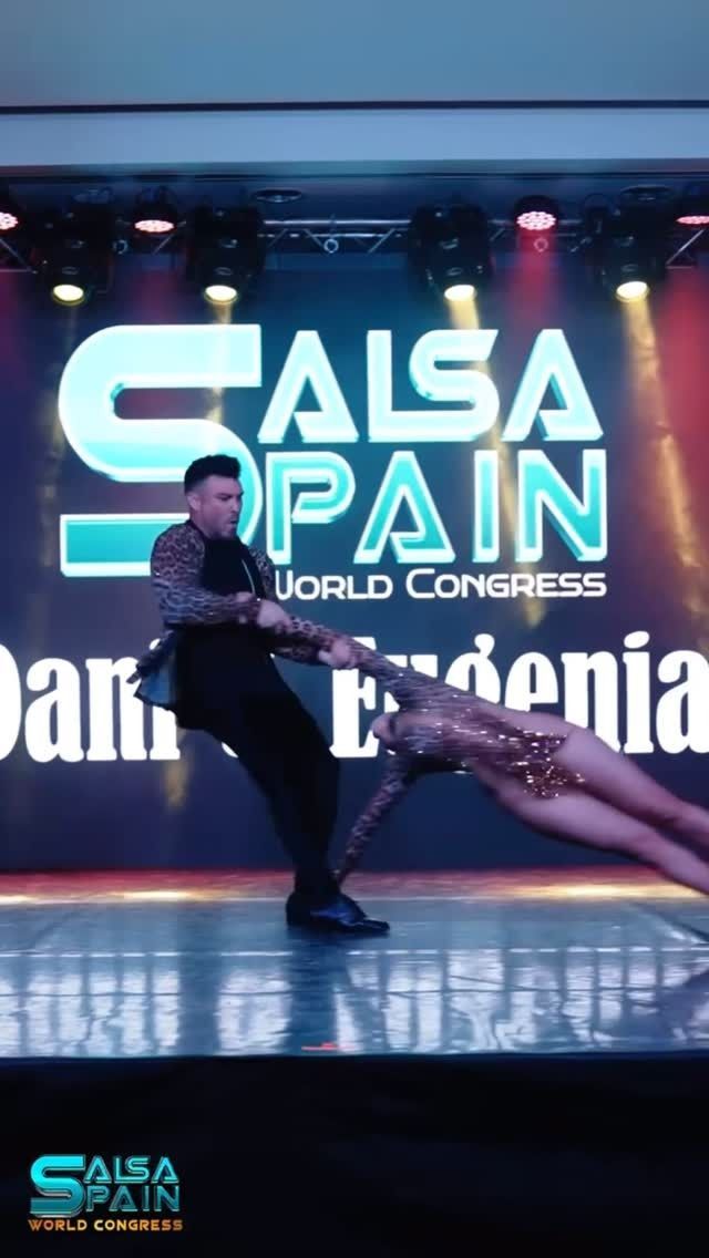 Un hombre y una mujer bailan frente a una pantalla grande que dice salsa españa