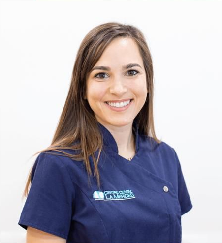 Mujer sonriente con uniforme médico azul sobre fondo blanco
