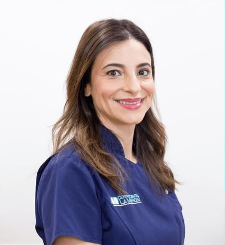 Mujer con uniforme médico azul sonriendo sobre un fondo blanco.