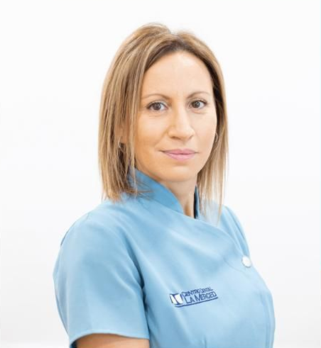Retrato de una enfermera con uniforme azul sobre un fondo blanco.