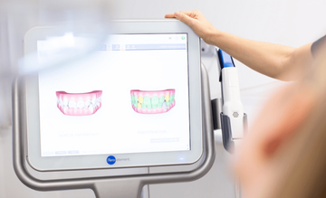 Dentista visualizando escaneo 3D de los dientes en un monitor táctil.