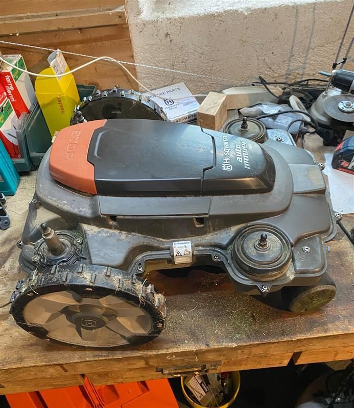 Une tondeuse à gazon est posée sur une table en bois.