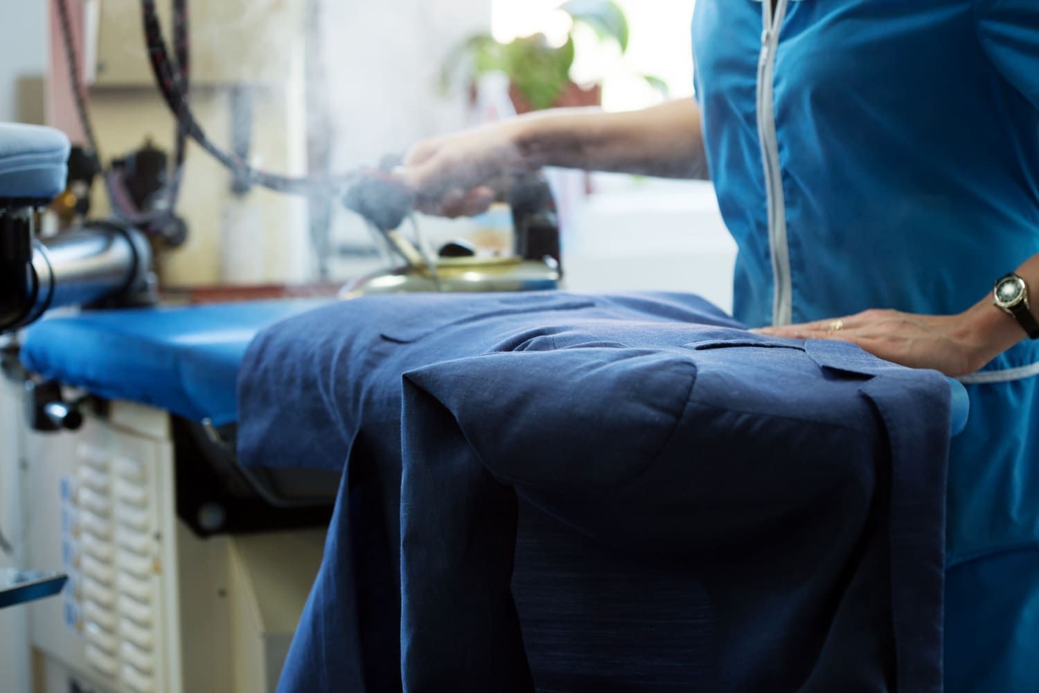 Una mujer está planchando una camisa azul en una tabla de planchar.