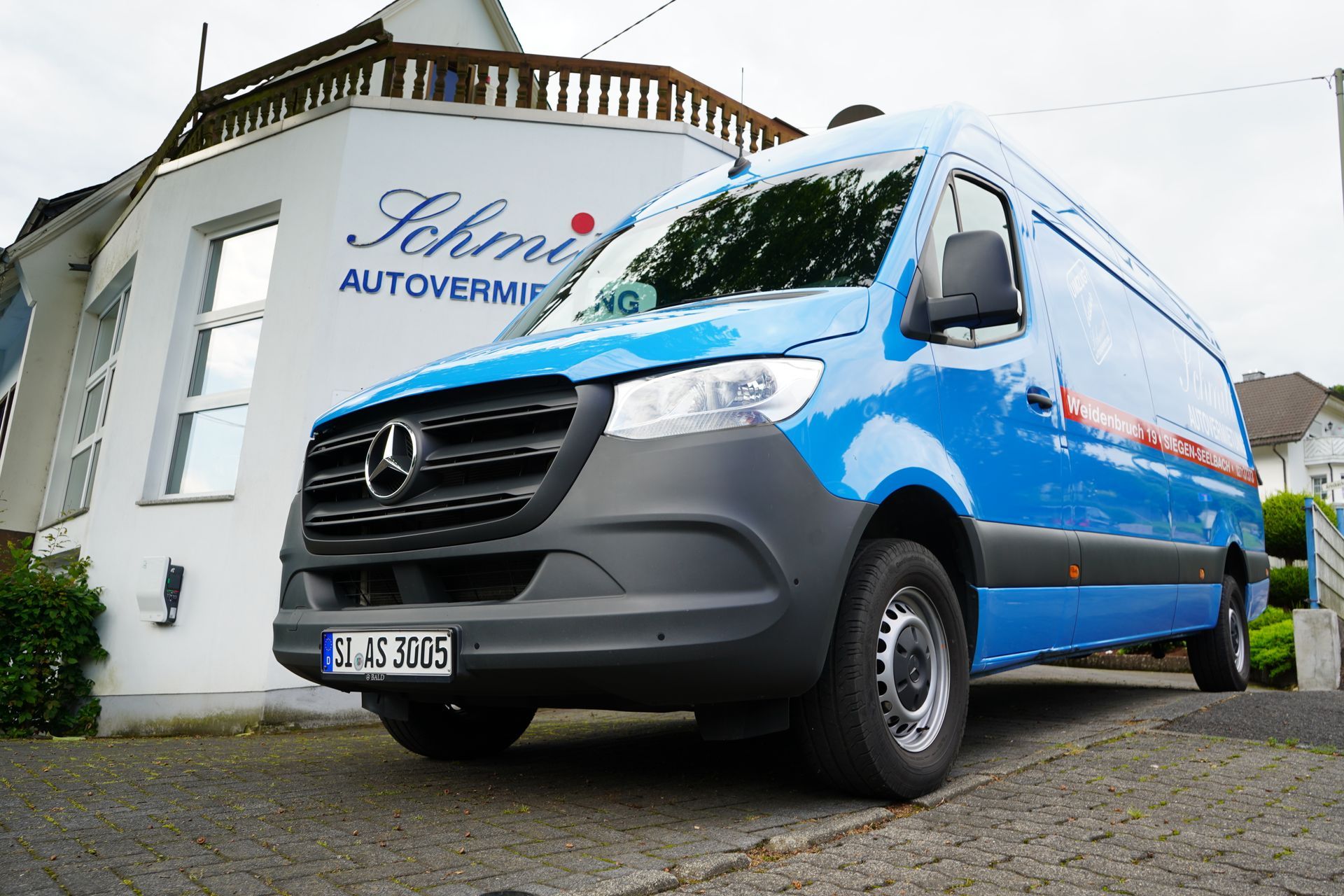 Ein blauer Mercedes-Van steht vor einem Gebäude.