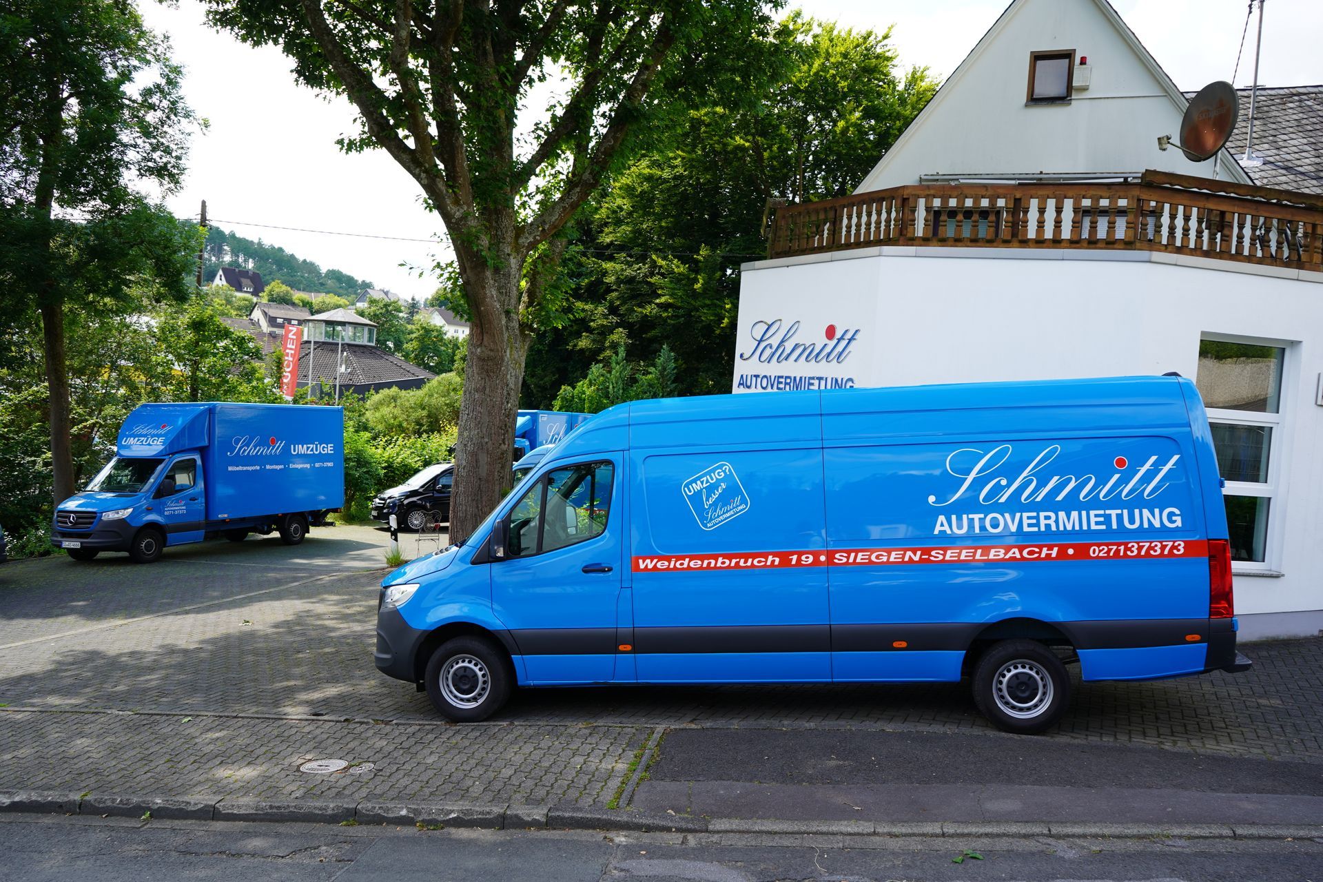 Zwei blaue Lieferwagen parken vor einem Gebäude.