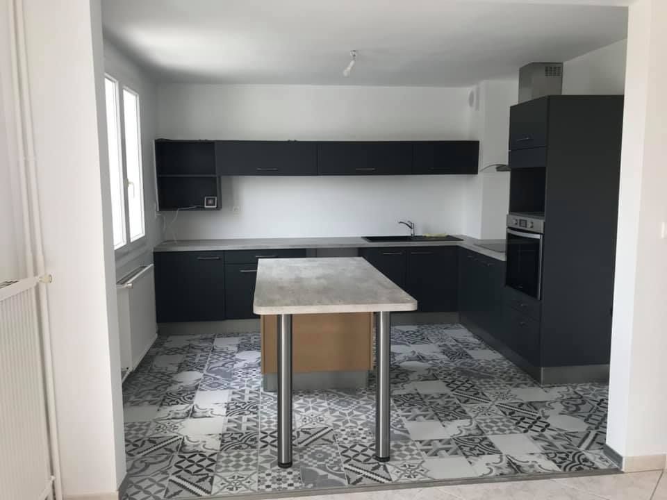 Cuisine blanche et noire rénovée avec mobilier réaménagé et table centrale installée