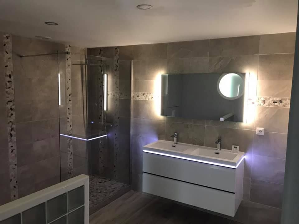 Rénovation d'une salle de bains avec la mise en place d'une cabine de douche, espace de lavabo avec néon et miroir éclairé