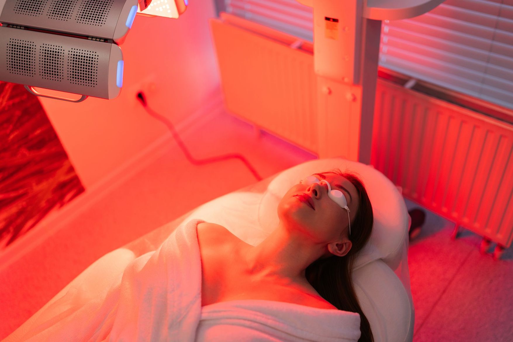 Patient allongé sur une table de traitement sous luminothérapie rouge dans une salle clinique