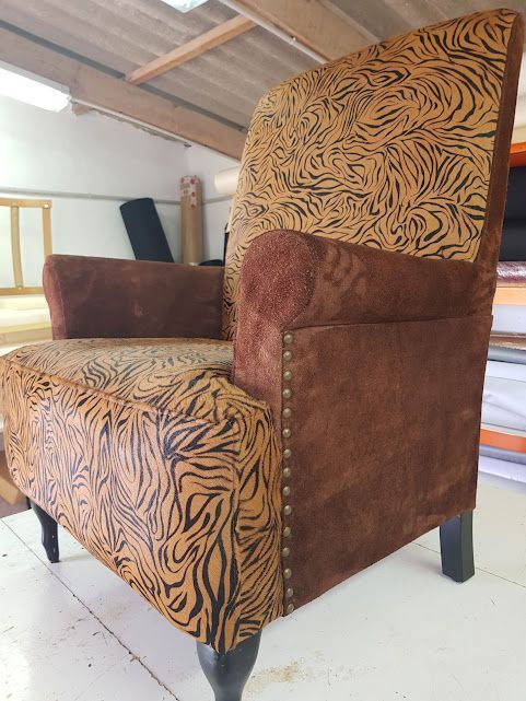 Sillón con estampado de tigre y marrón, con patas oscuras.