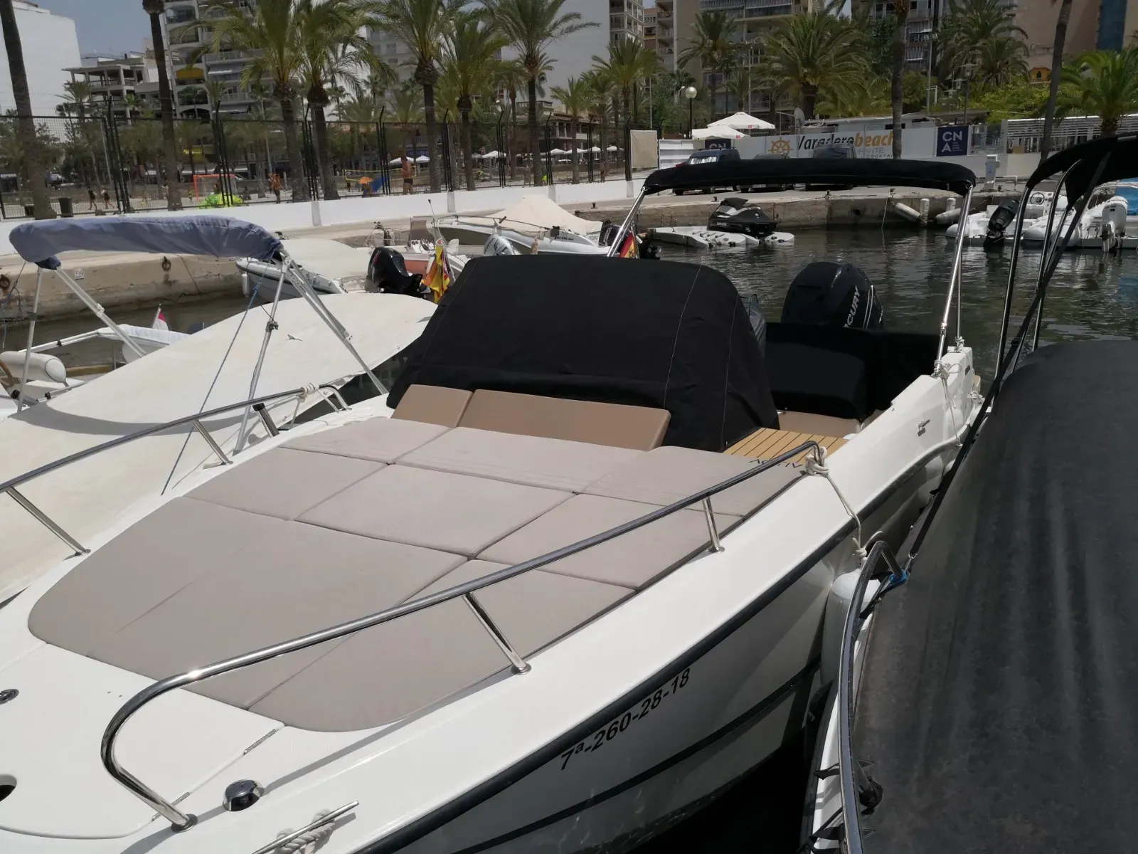 Asientos en un barco de cuero rojo alrededor de una mesa de madera, con vistas a un puerto con yates atracados.