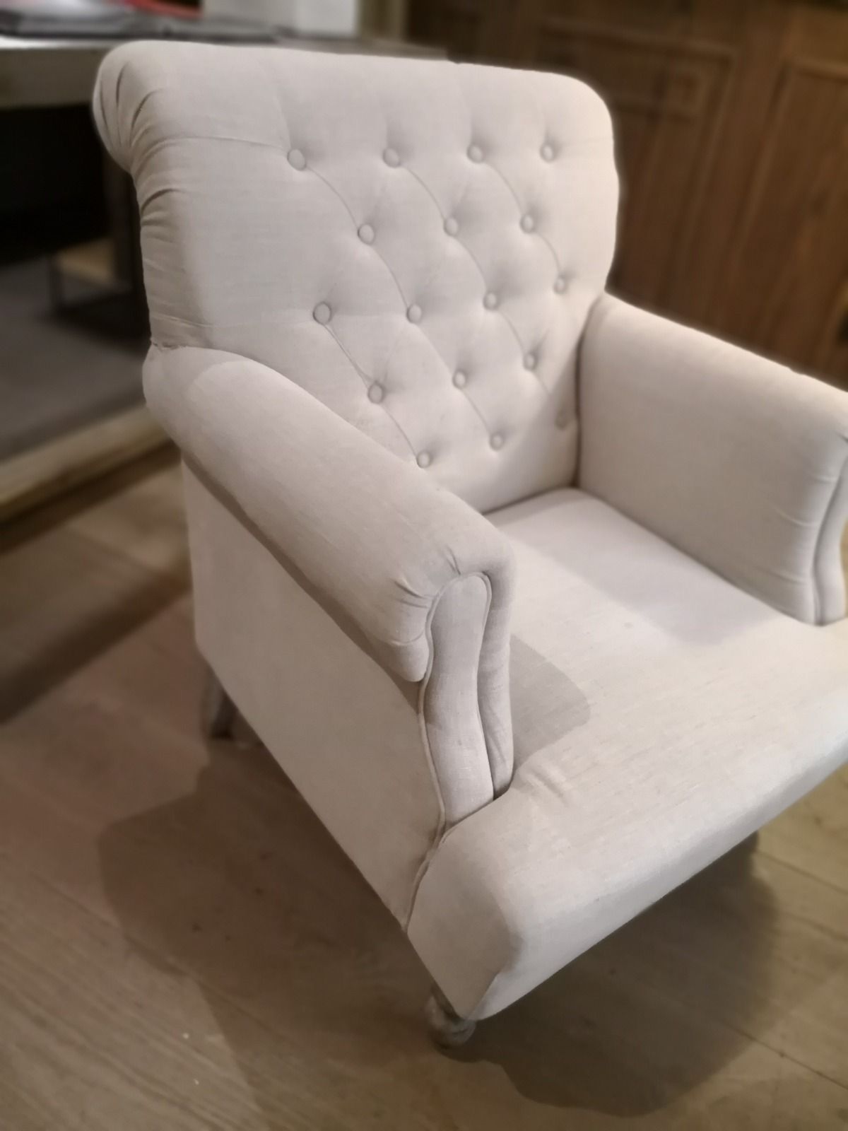 Sofás y taburetes negros con mechones capitoné y mesas con cubierta de mármol en un salón poco iluminado.