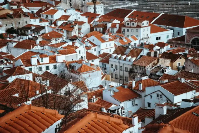 Vista aérea de una densa ciudad en la ladera de una colina, con edificios blancos y tejados de tejas de terracota.