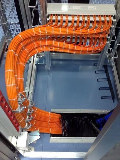 Ein Elektriker prüft die Verkabelung in einem offenen Verteilerkasten mit einem digitalen Multimeter.