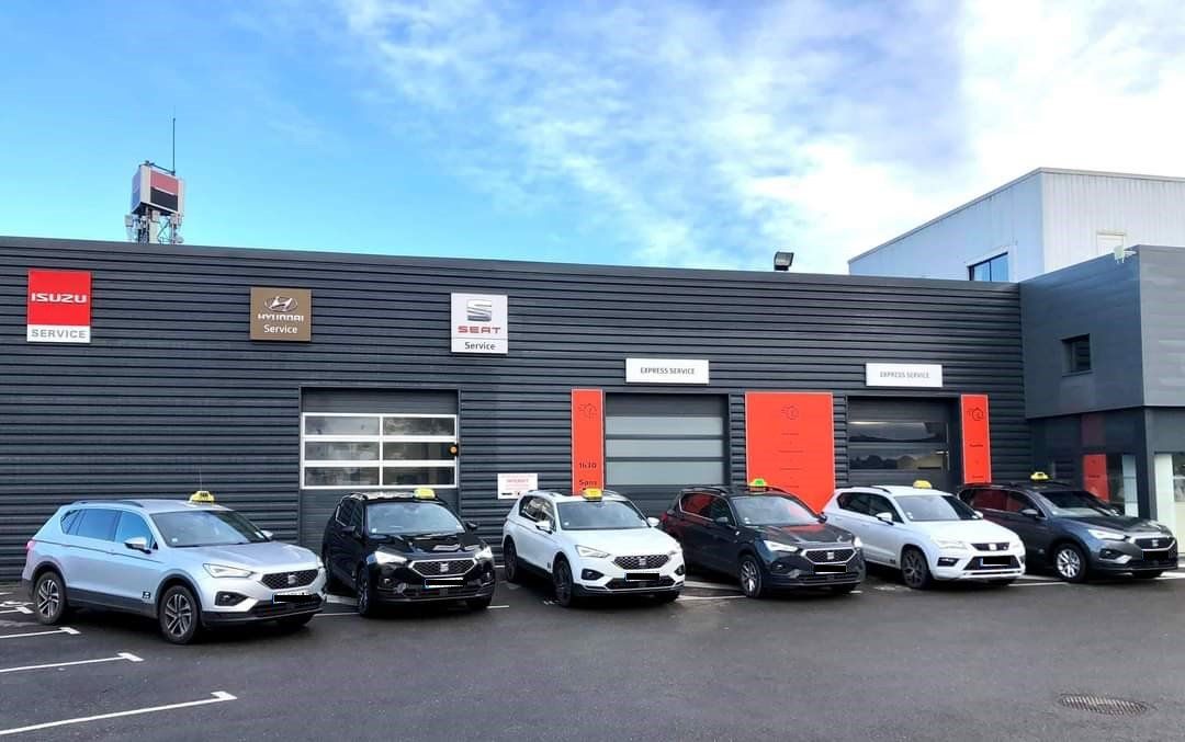 Véhicules de l'agence ABC Alès Taxi stationnés devant un garage