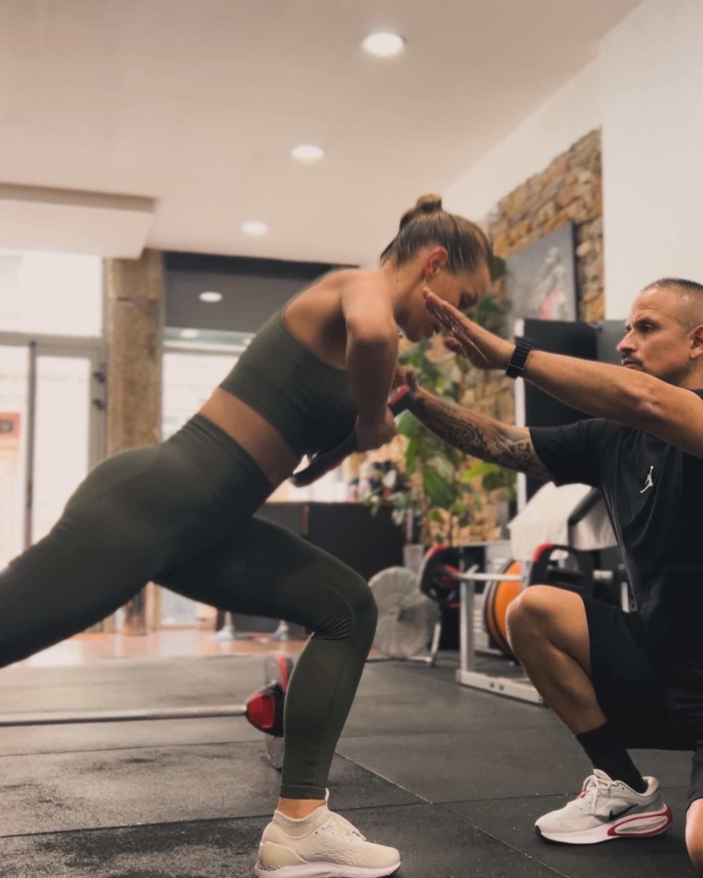 Femme en tenue de sport qui fait une fente, coach sportif devant elle