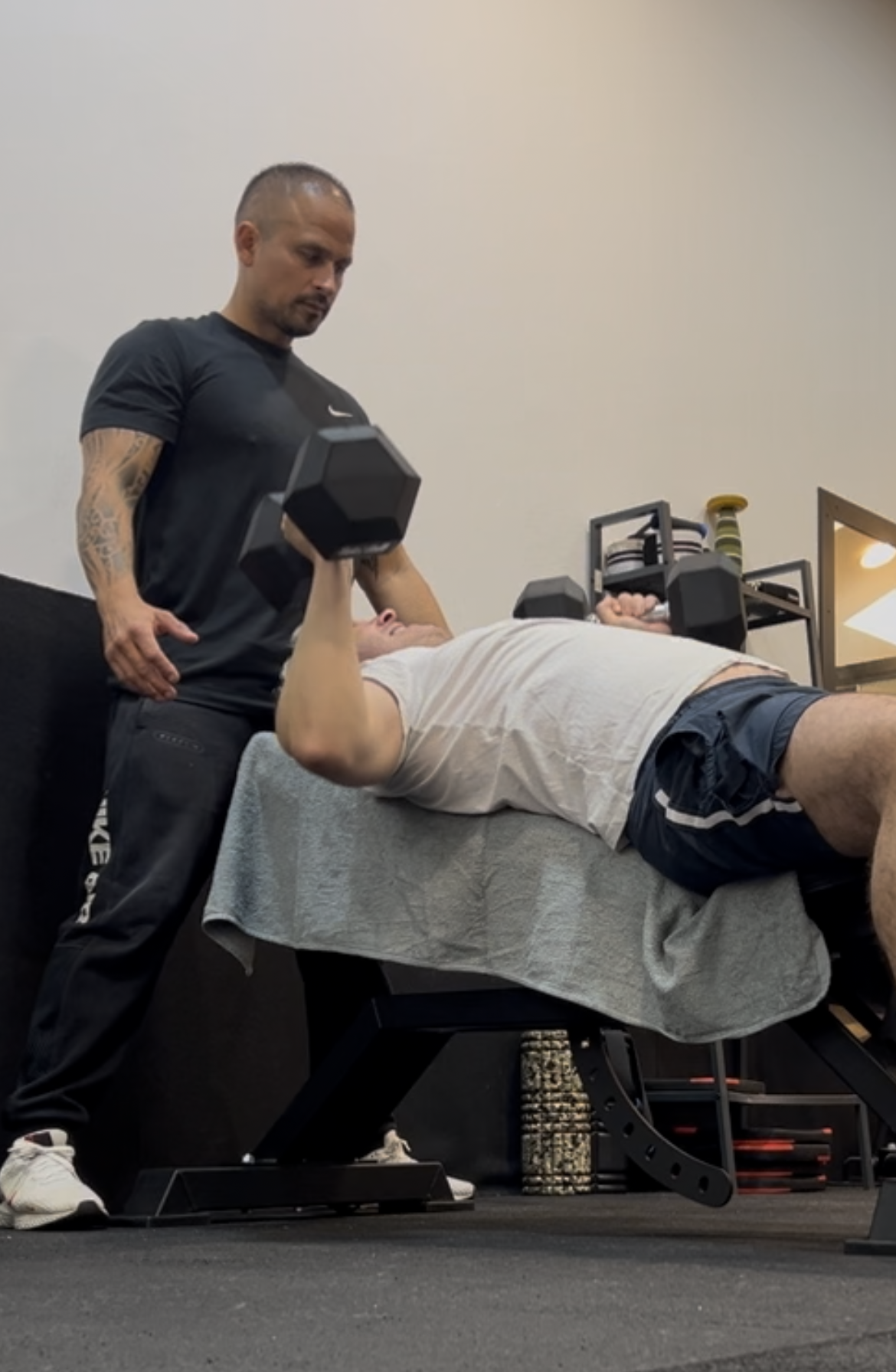 Coach sportif debout derrière un homme allongé en tenue de sport