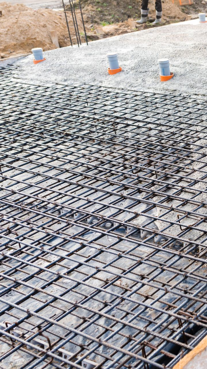 Grille en acier armé au-dessus de gravier, avec canalisations. Chantier.