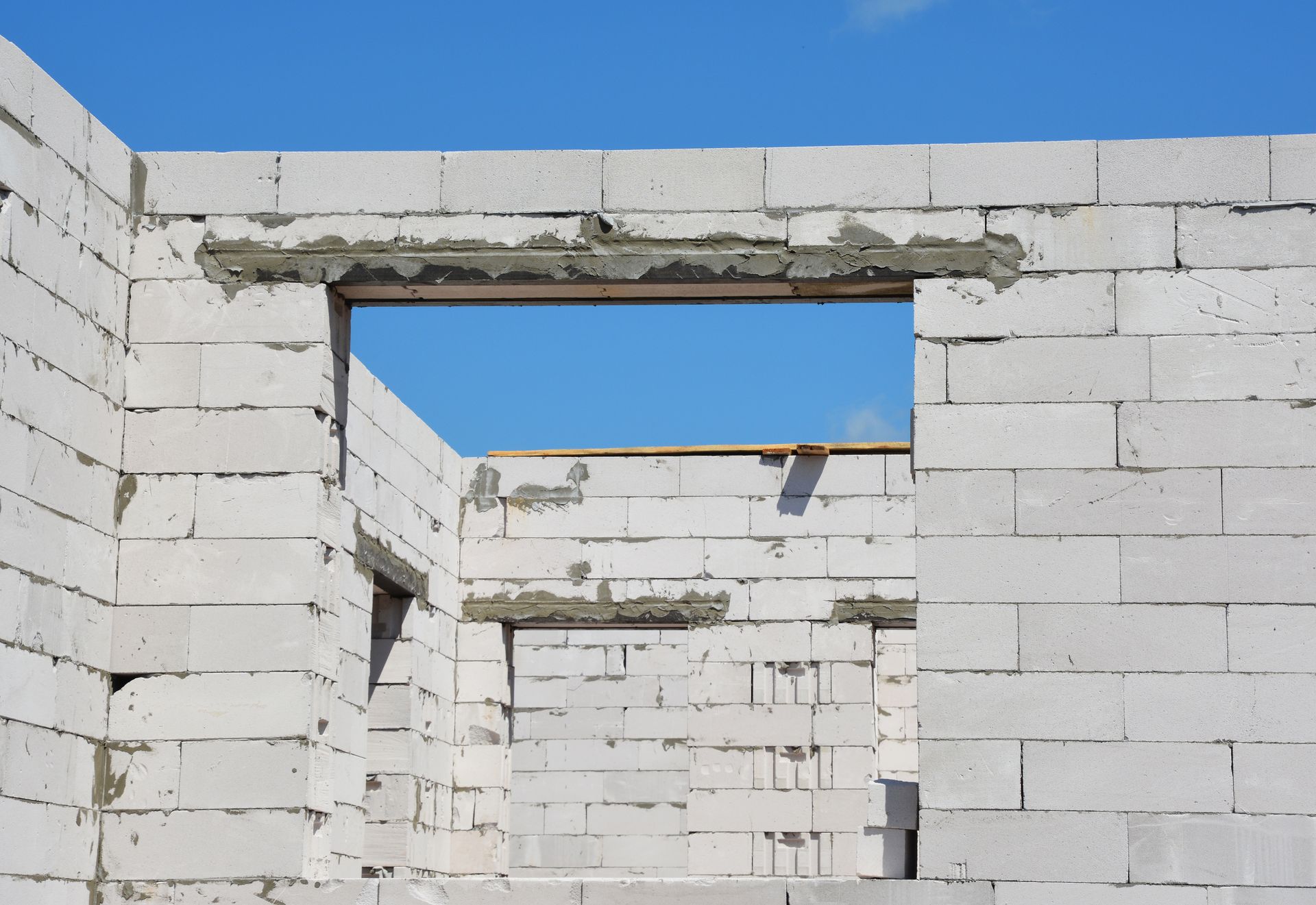 Bâtiment inachevé avec des ouvertures rectangulaires pour les fenêtres, ciel bleu visible.