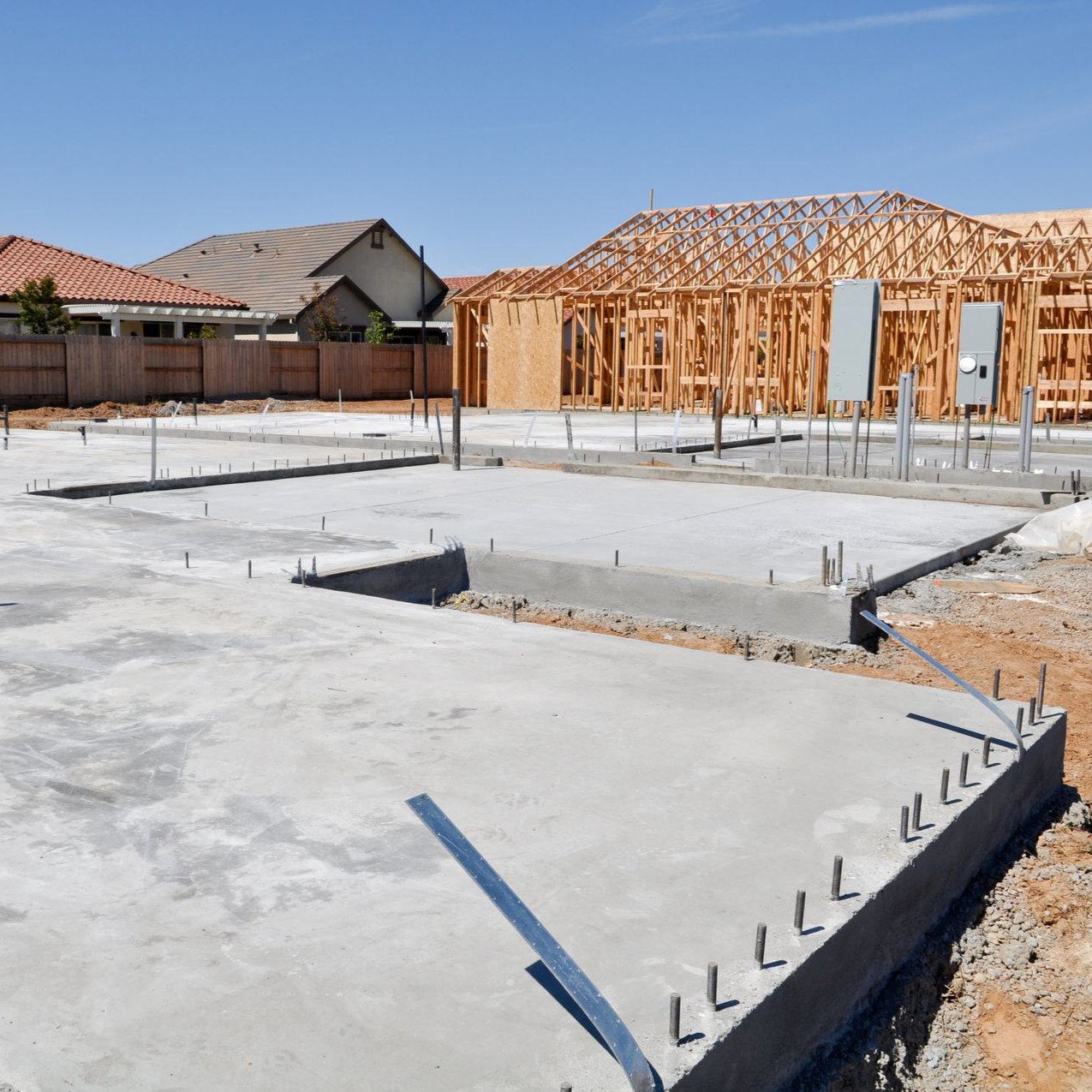 Chantier de construction avec fondations en béton et charpente en bois.