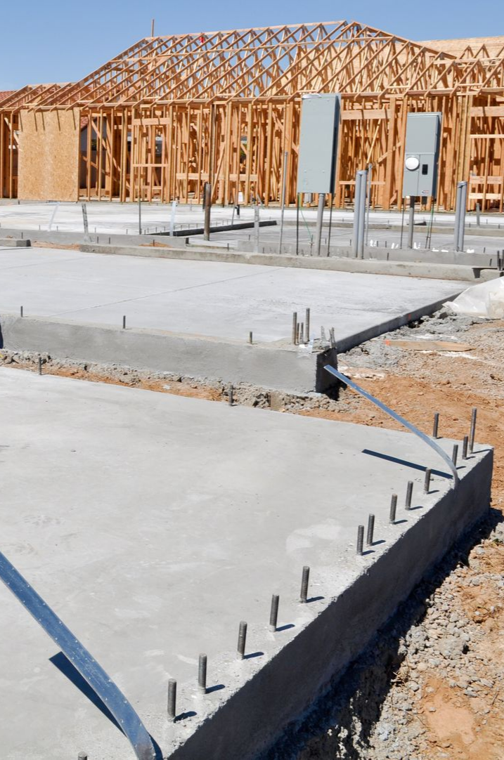 Chantier de construction avec fondations en béton et ossature bois.