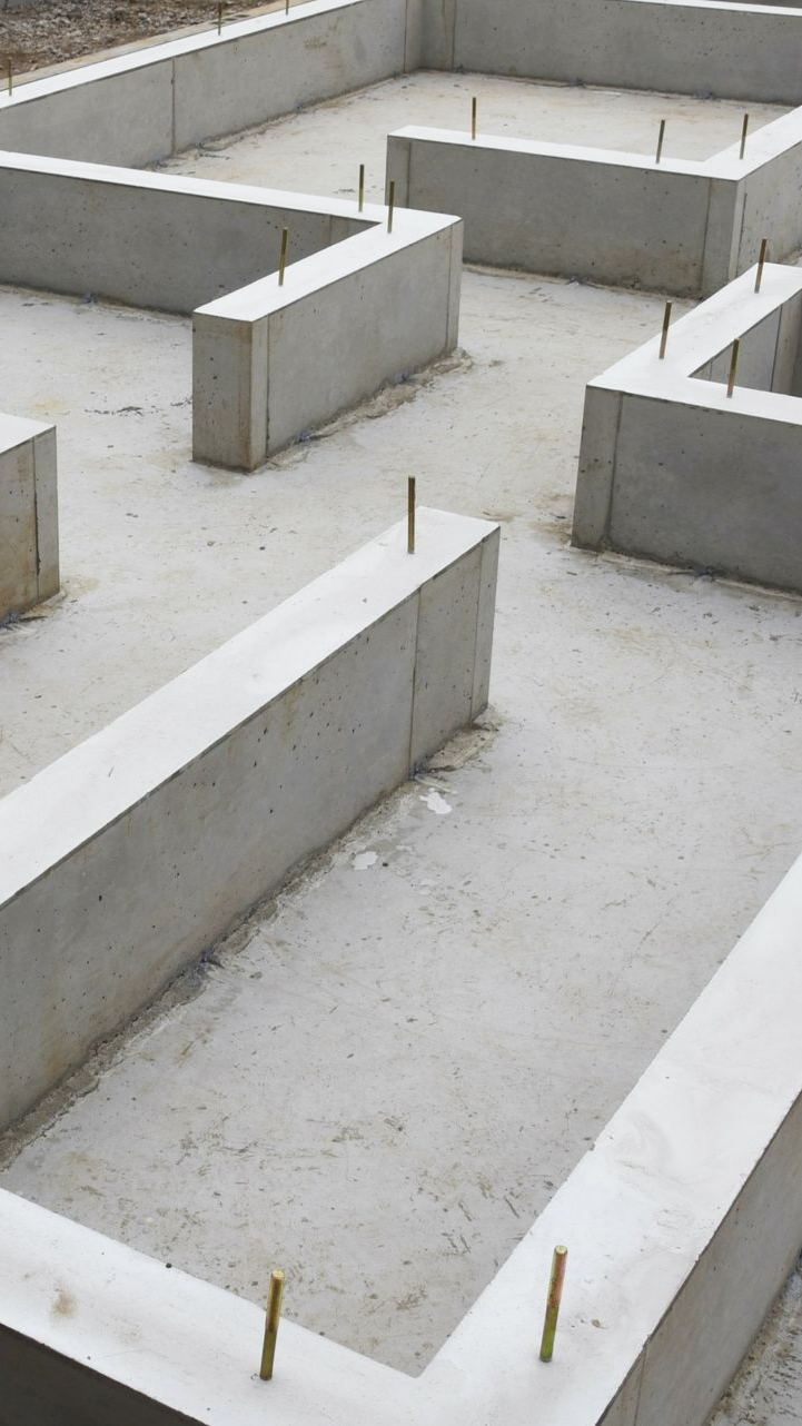 Murs de fondations en béton avec tiges métalliques saillantes, prêts pour la construction.