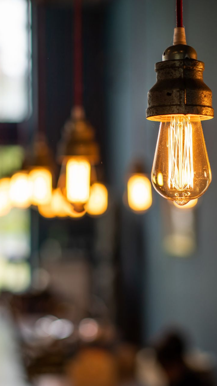 Des ampoules vintage suspendues s'illuminent sur un fond flou. Une lumière chaude et chaleureuse.