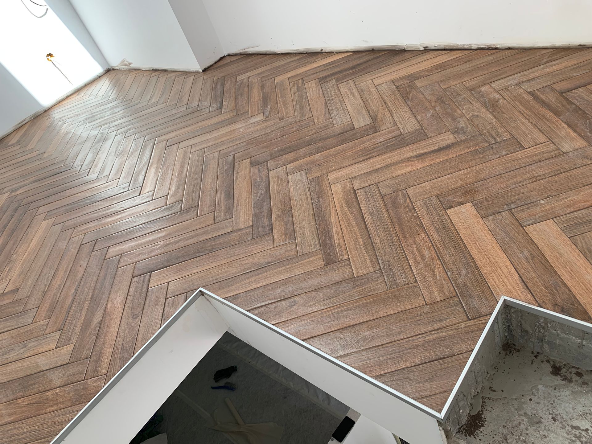 Parquet à chevrons avec plinthes blanches.