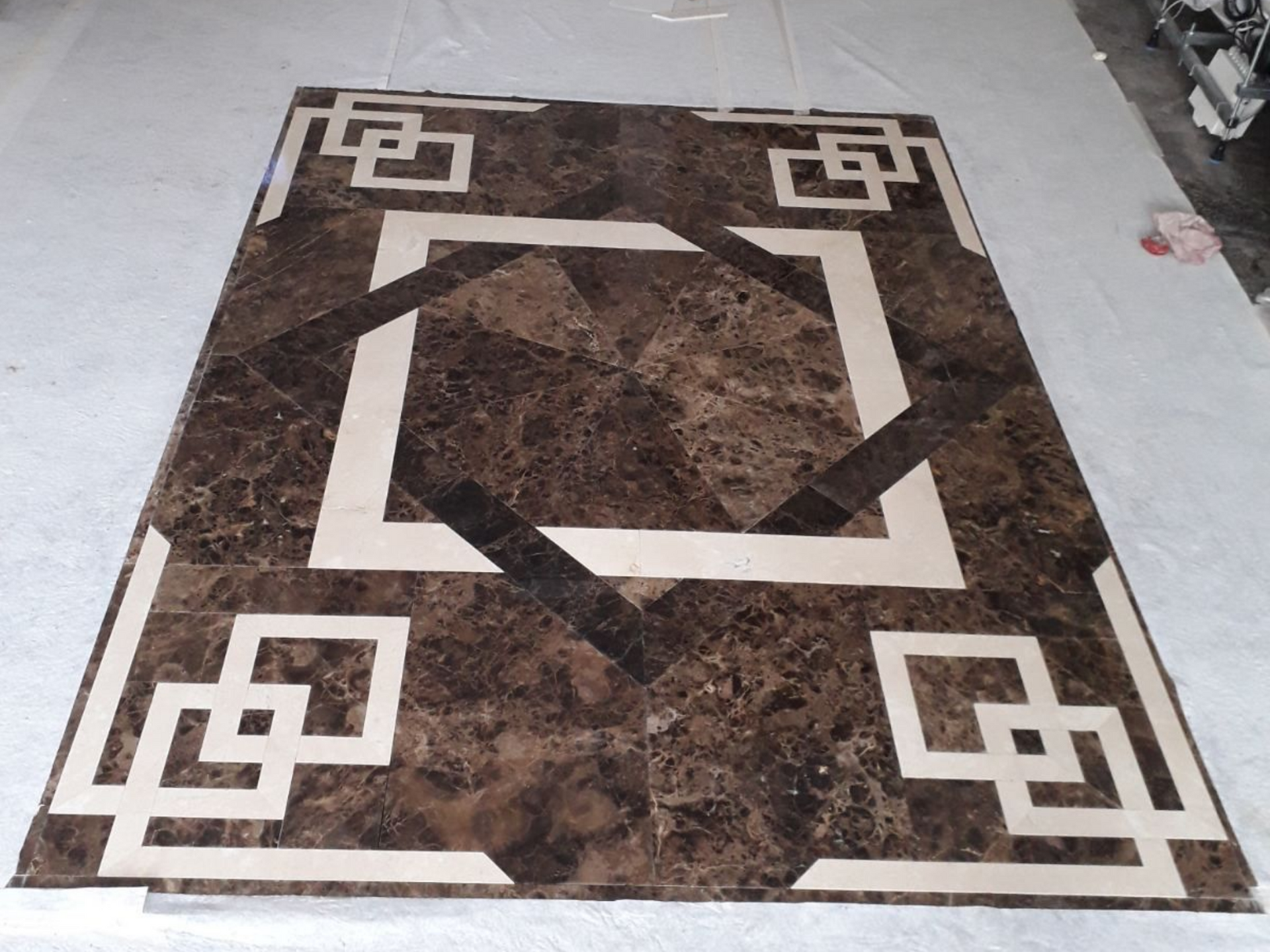 Carrelage en marbre brun et crème à motifs géométriques sur fond blanc.