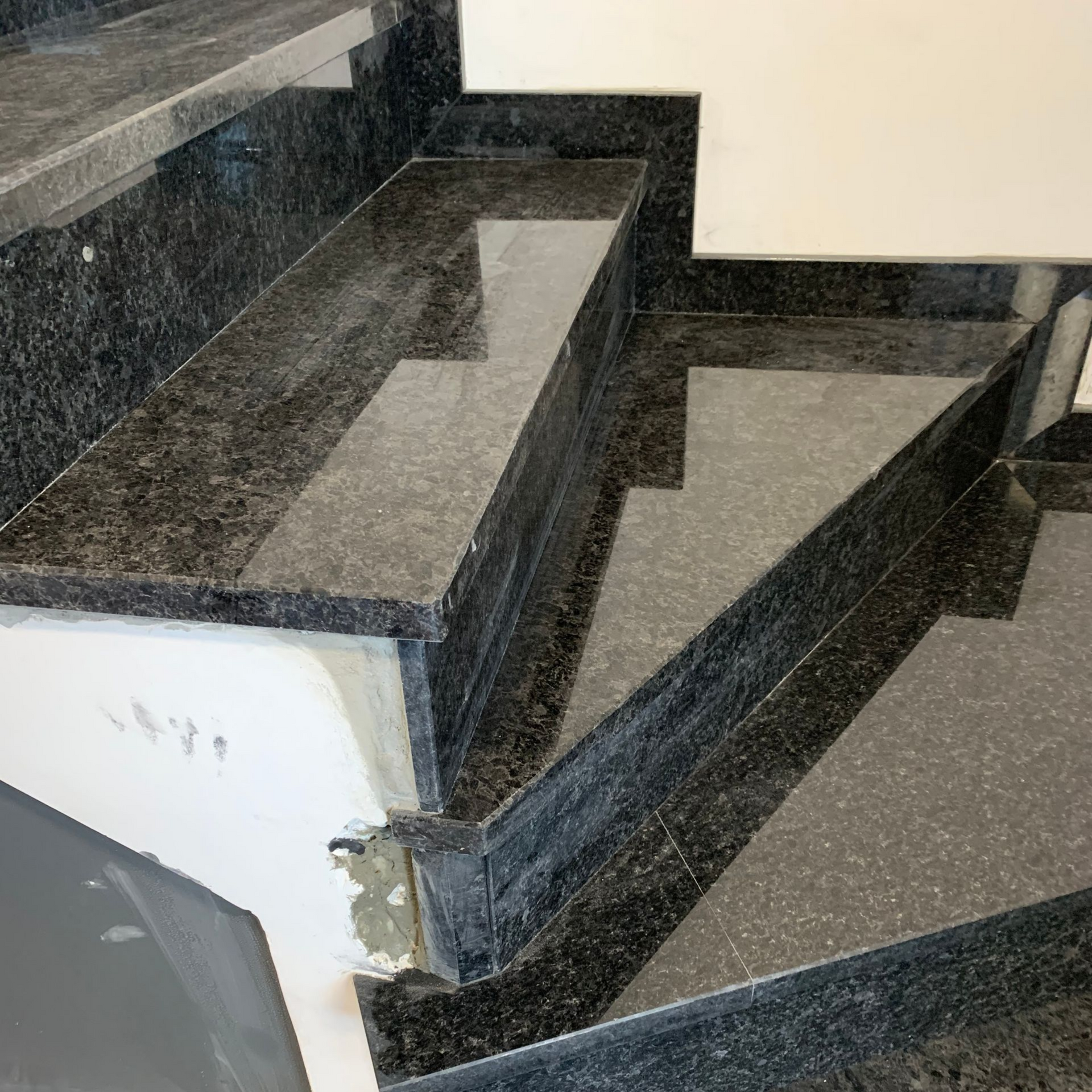 Escalier en granit noir et murs blancs.