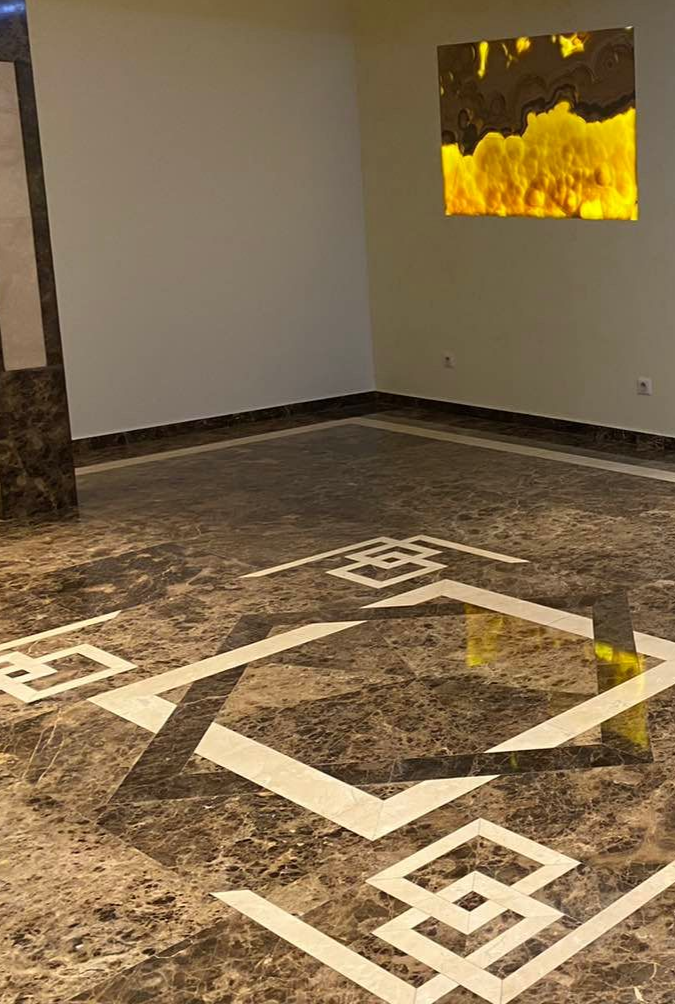 Pièce avec un sol carrelé de carreaux bruns à motifs et un carré ambré lumineux en haut à droite. Murs blancs.