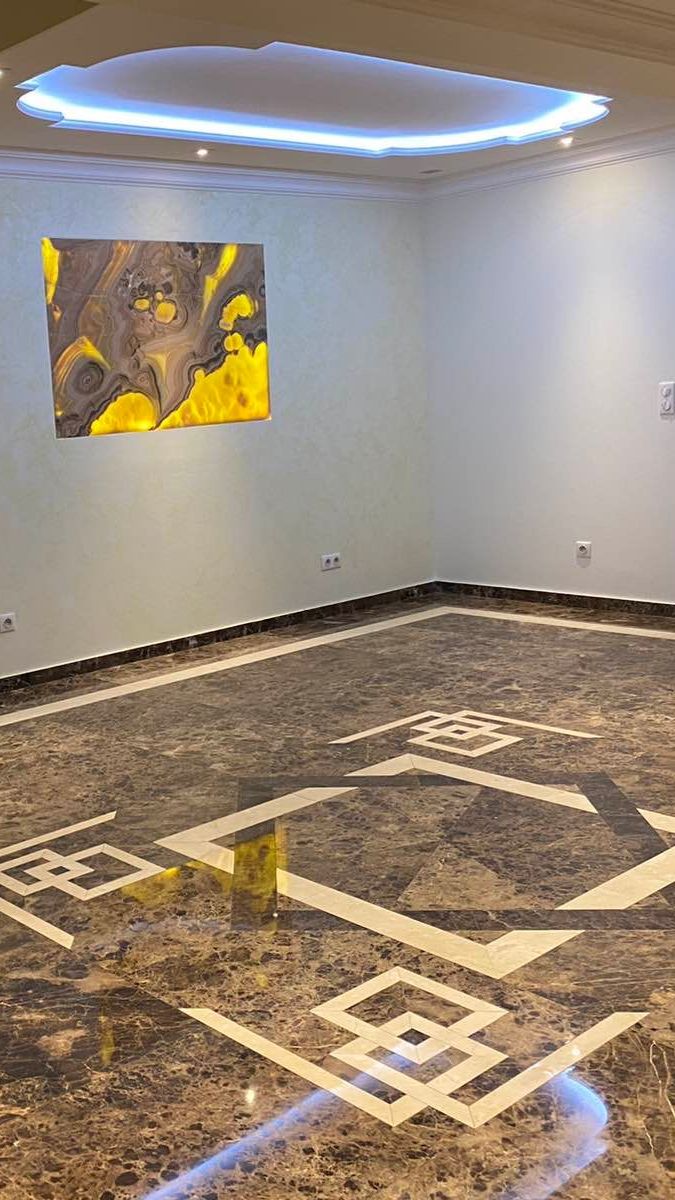 Un carreleur pose un sol à l'aide de clips de nivellement. Les carreaux sont posés sur de la colle, les outils sont à proximité.