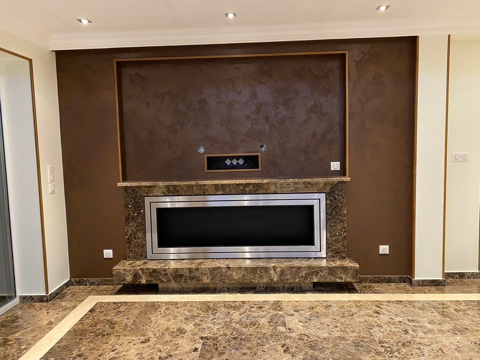 Mur marron avec cheminée et détails en marbre.