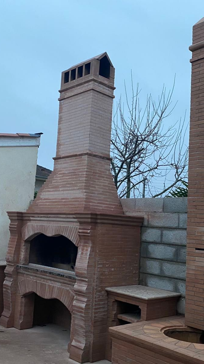 Cheminée extérieure en briques avec conduit de cheminée sur fond de ciel nuageux.