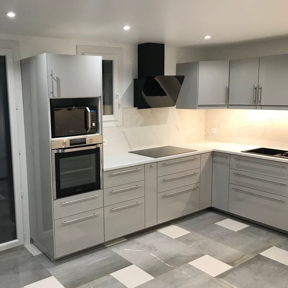 Cuisine moderne avec placards gris, électroménager intégré et sol carrelé gris et blanc.