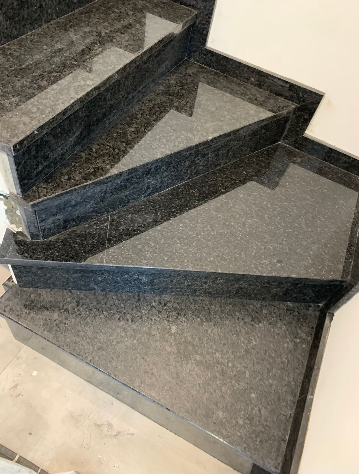 Escaliers en granit gris foncé, dans un bâtiment. Les marches et les contremarches sont visibles.