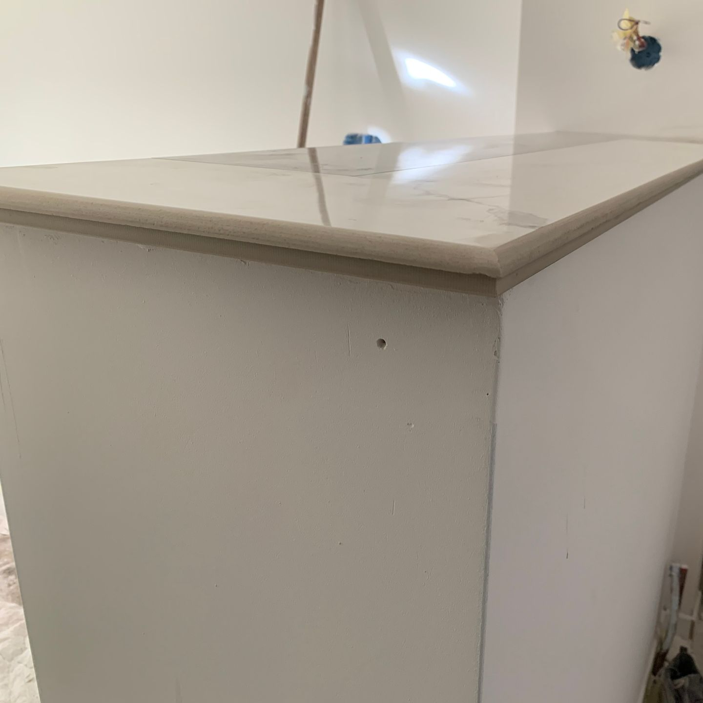 Plan de travail blanc avec plateau en marbre et bordure gris clair.