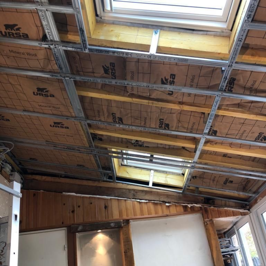 Construction du plafond avec isolation, ossature métallique et puits de lumière.