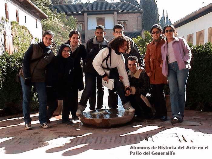 Grupo de personas alrededor de una fuente en un patio. Edificios al fondo.