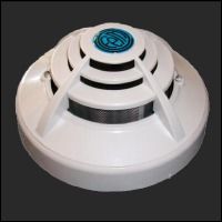 Un detector de humo blanco está colocado encima de una superficie negra.
