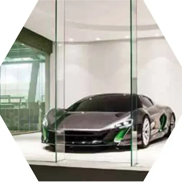 Un coche deportivo gris está aparcado en un garaje de cristal.