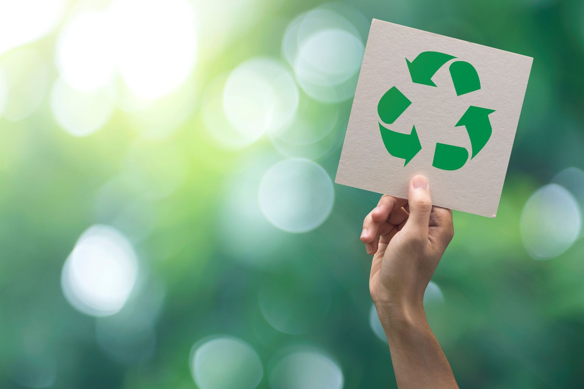 Una persona sostiene un trozo de papel con un símbolo de reciclaje.