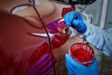 Rotes Auto in der Werkstatt beim Lackieren Rotes Auto in der Werkstatt beim Lackieren