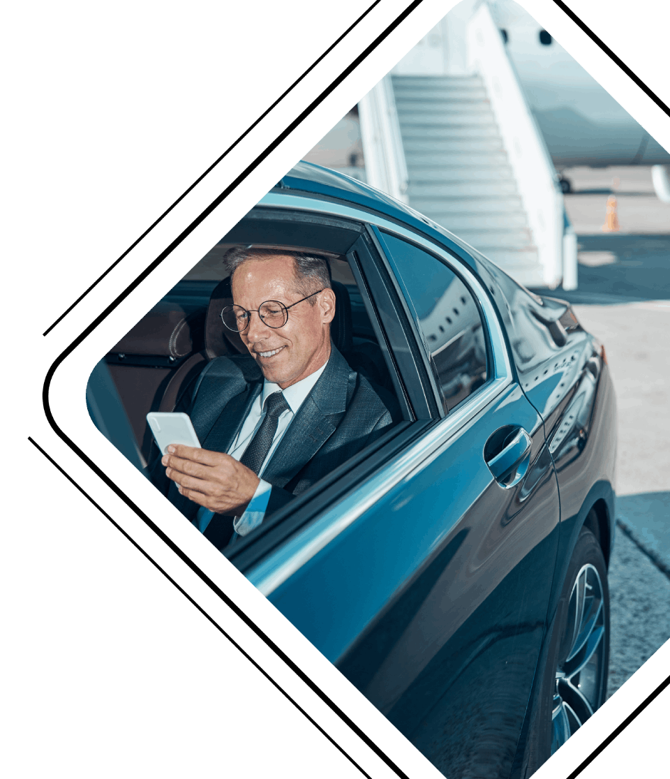 man zittend in een auto kijkend naar telefoon