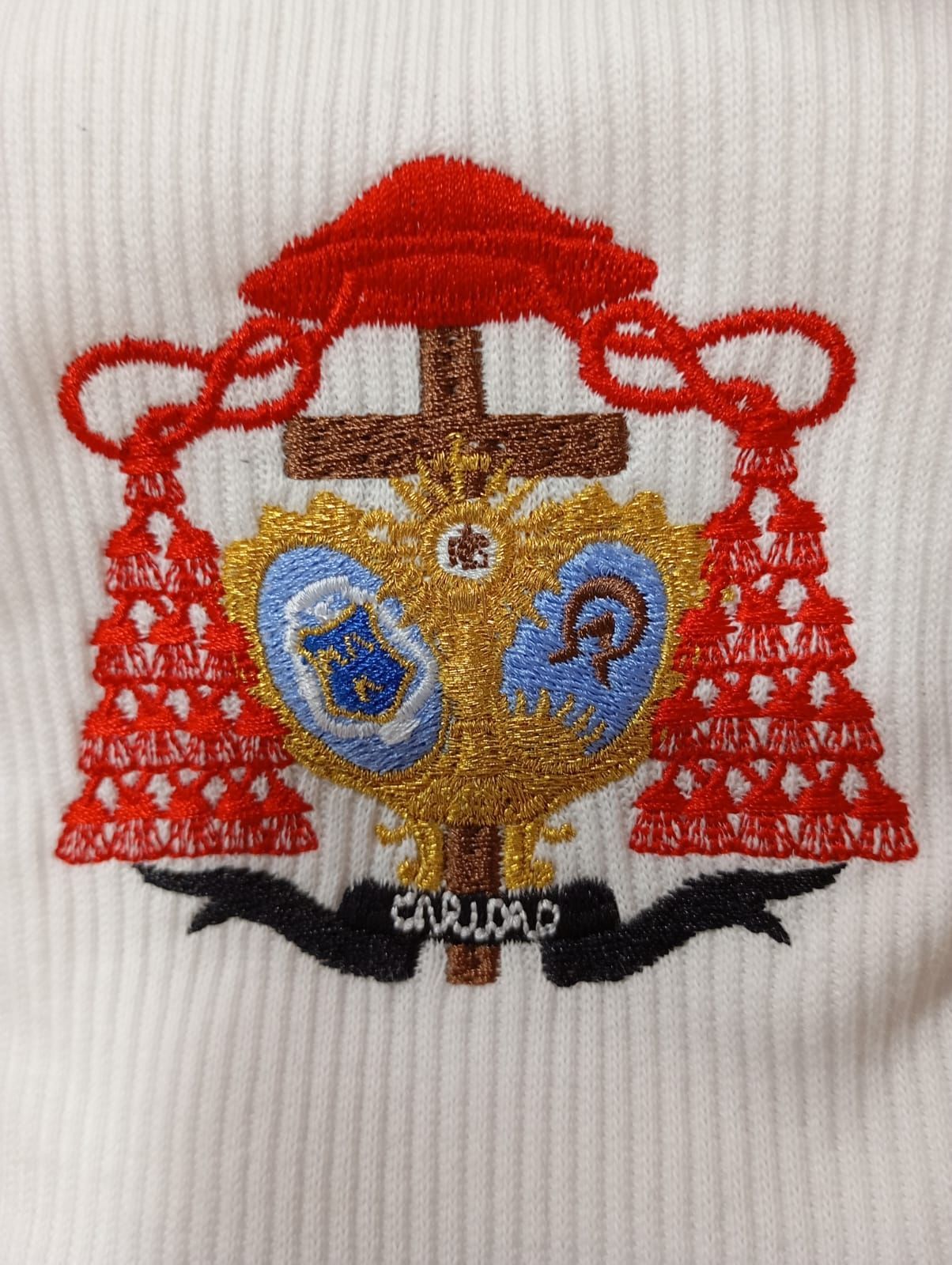 Un suéter blanco con un escudo de armas bordado.