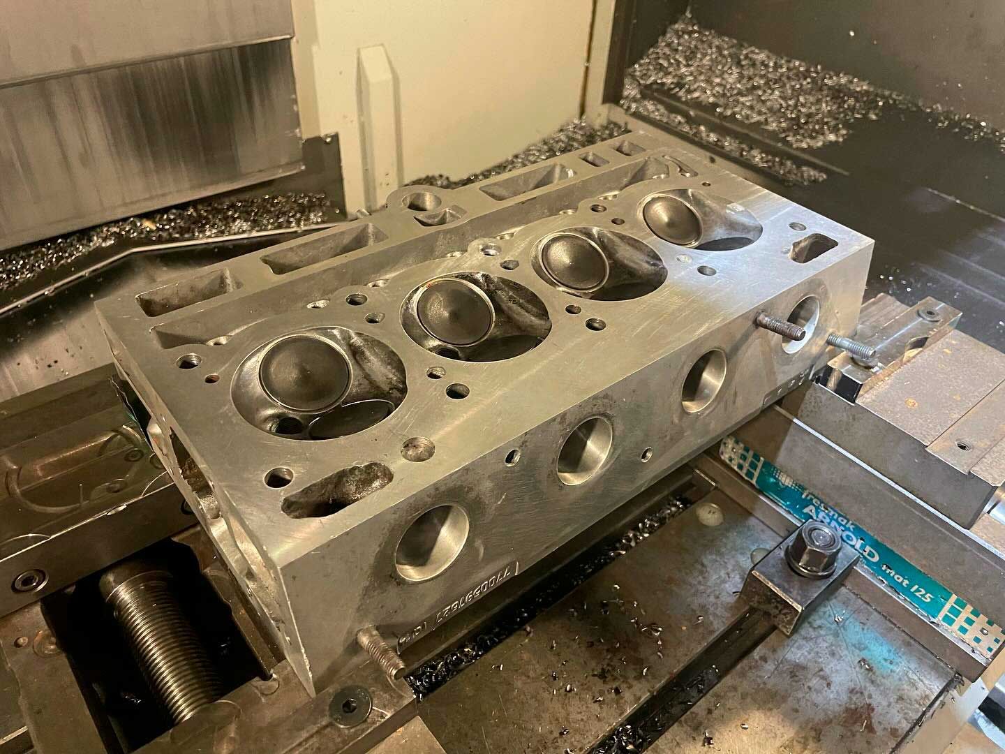 Se está mecanizando una culata de metal en una máquina.