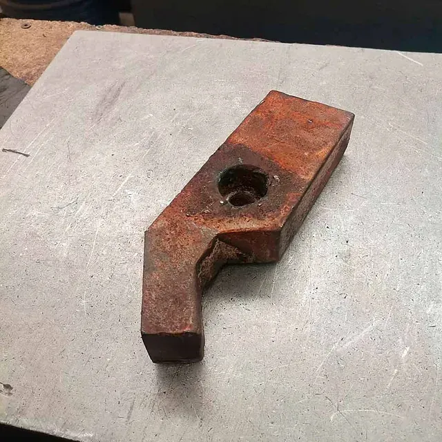 Un trozo de metal oxidado con un agujero está sobre una mesa.