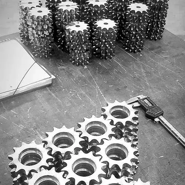Una fotografía en blanco y negro de una pila de engranajes sobre una mesa.