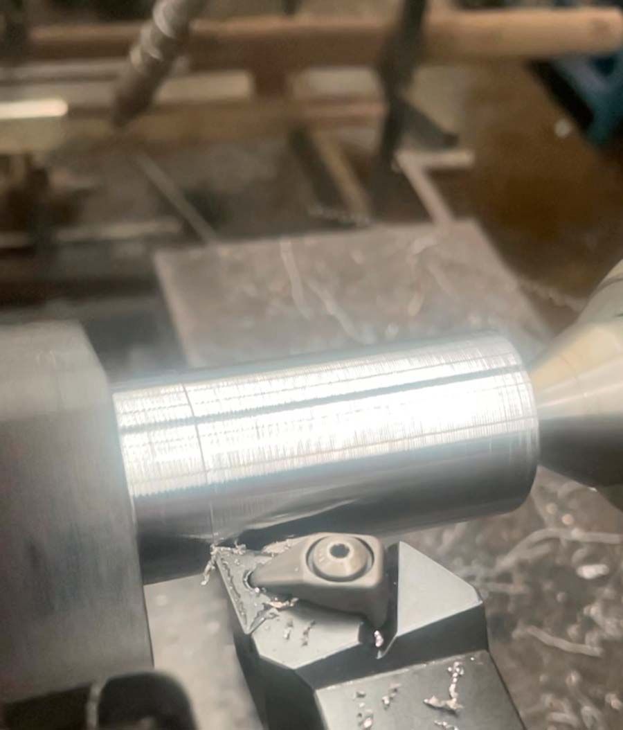 Un primer plano de una máquina cortando un trozo de metal sobre una mesa.