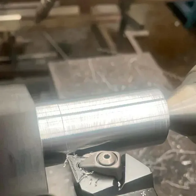 Una máquina está cortando un trozo de metal en un torno.
