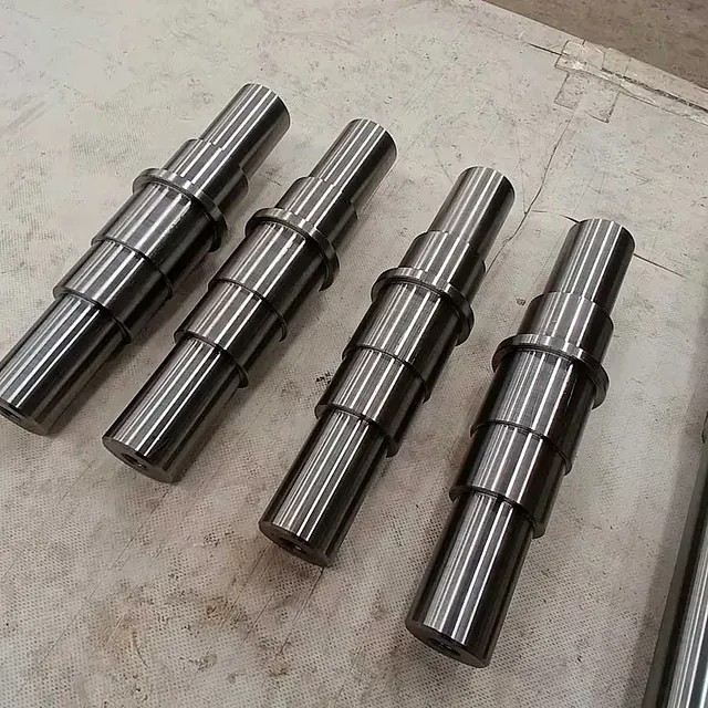 Cuatro ejes de acero inoxidable están alineados sobre una mesa.